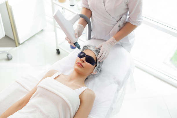 Facial rejuvenation. Nice positive woman wearing protective eyewear while receiving professional beauty treatment